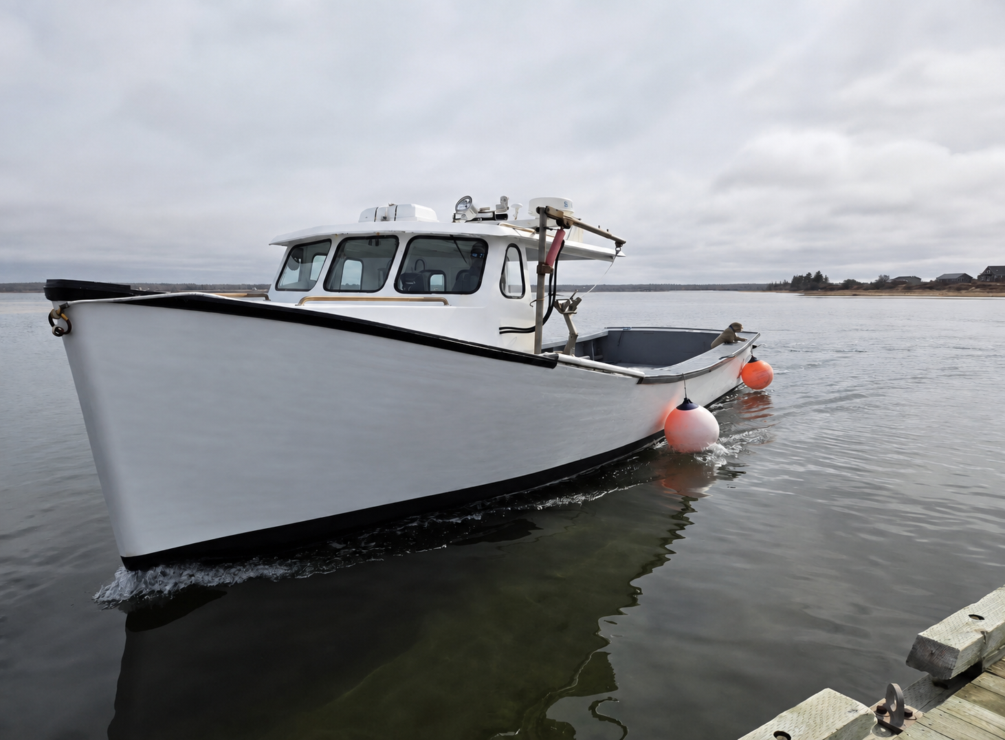 A white fishing boat with a black hull stripe and cabin, floating on calm water under an overcast sky. Orange buoys are attached to the side of the boat, and a dock is visible in the bottom right corner.