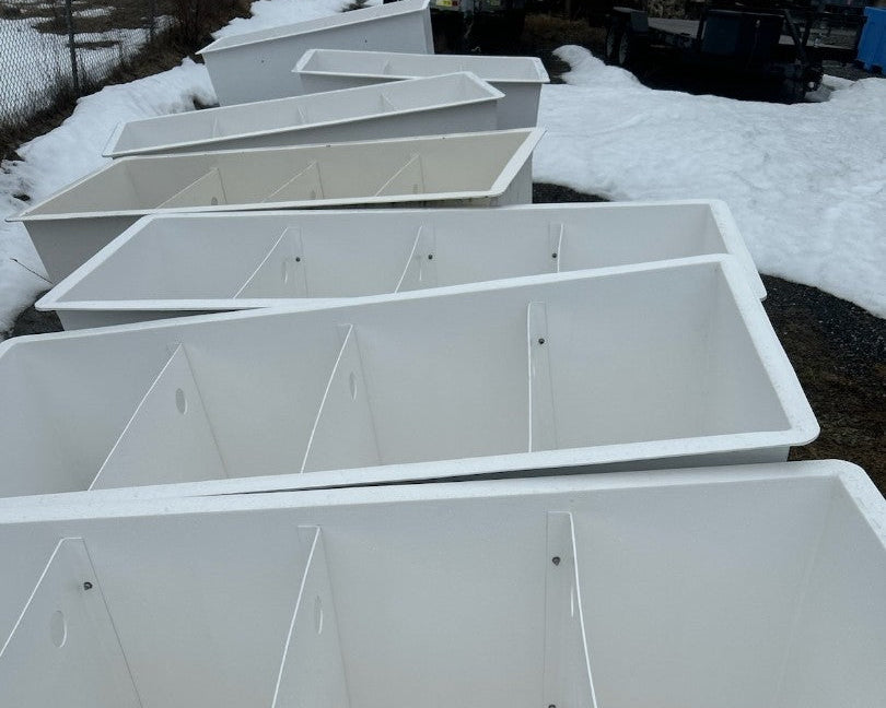 Row of white storage bins outdoors on a snowy ground