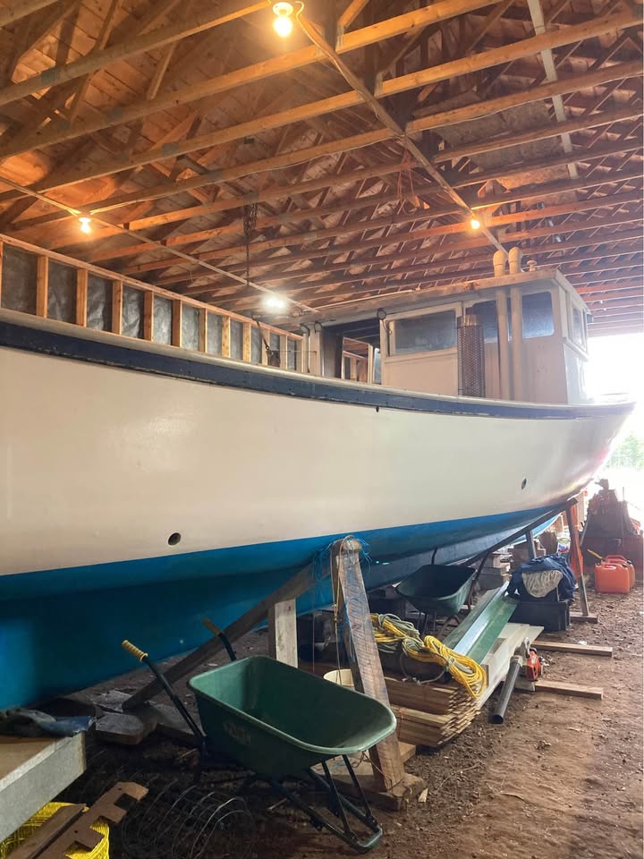 Boat inside a wooden building with tools and equipment around