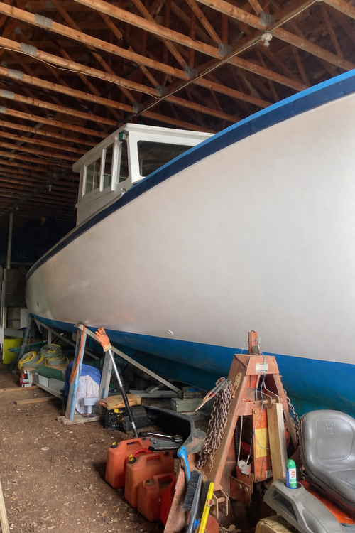 Large white boat with blue trim inside a wooden building