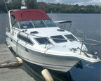 White boat with a red canopy docked at a wooden pier on a lake.