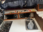 Compact kitchen area with sink, stove, and various items on a countertop.