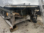 Boat on a wooden pallet with a tarp covering it, on a concrete surface.