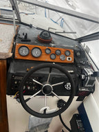 Boat steering wheel and dashboard with gauges inside a boat cabin.