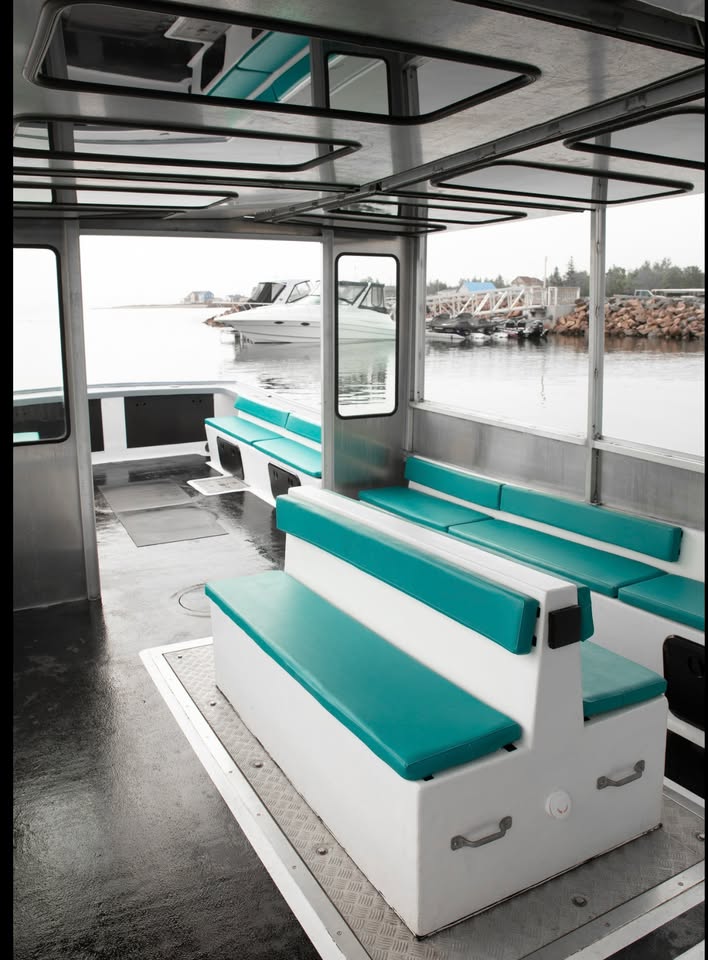Interior of a boat with teal and white seating area, water view outside