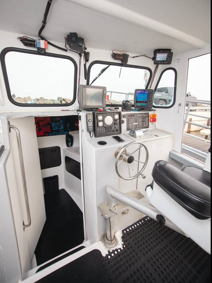 Control room of a boat with various instruments and steering wheel.