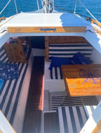 Sailboat interior with striped cushions and wooden furniture on a sunny day.
