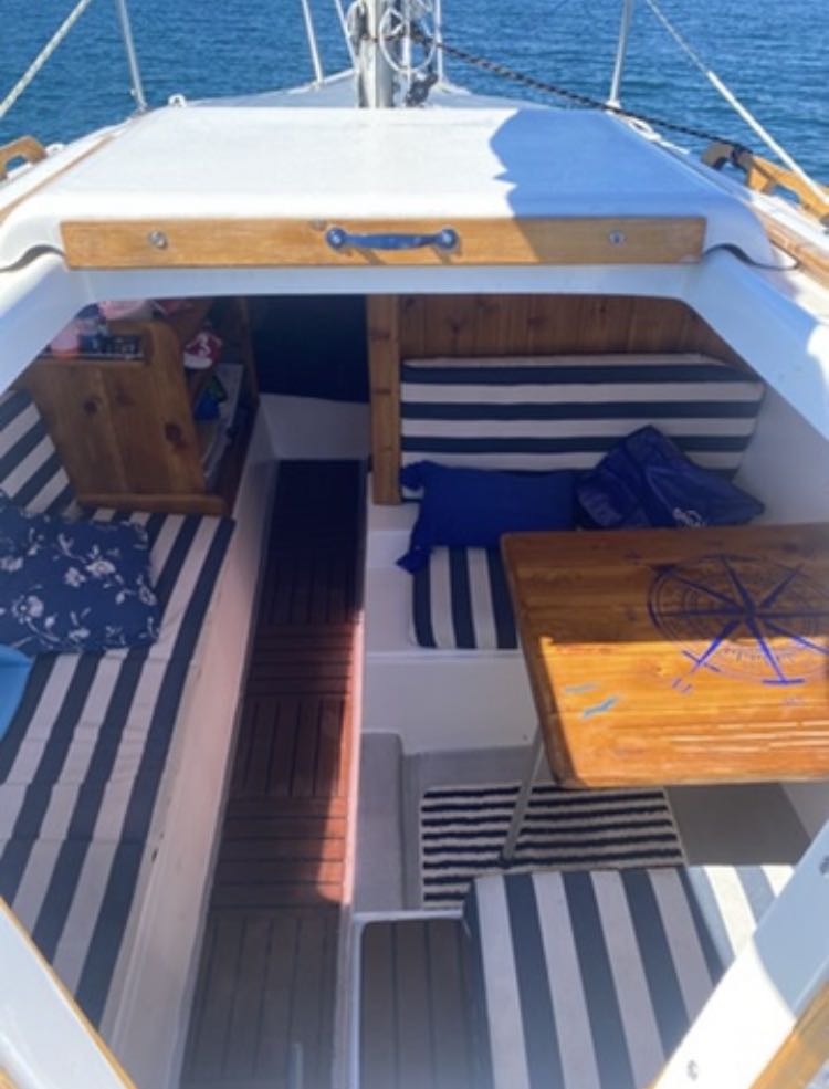 Sailboat interior with striped cushions and wooden furniture on a sunny day.