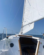 Sailboat with white sail on a clear blue sky day