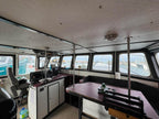 Interior of a boat with steering wheel, dashboard, and large windows showing water outside.