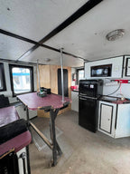 Small interior of a recreational vehicle with a table, refrigerator, and sink.