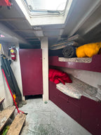 Bunk bed inside a vehicle with red blanket and yellow item on top
