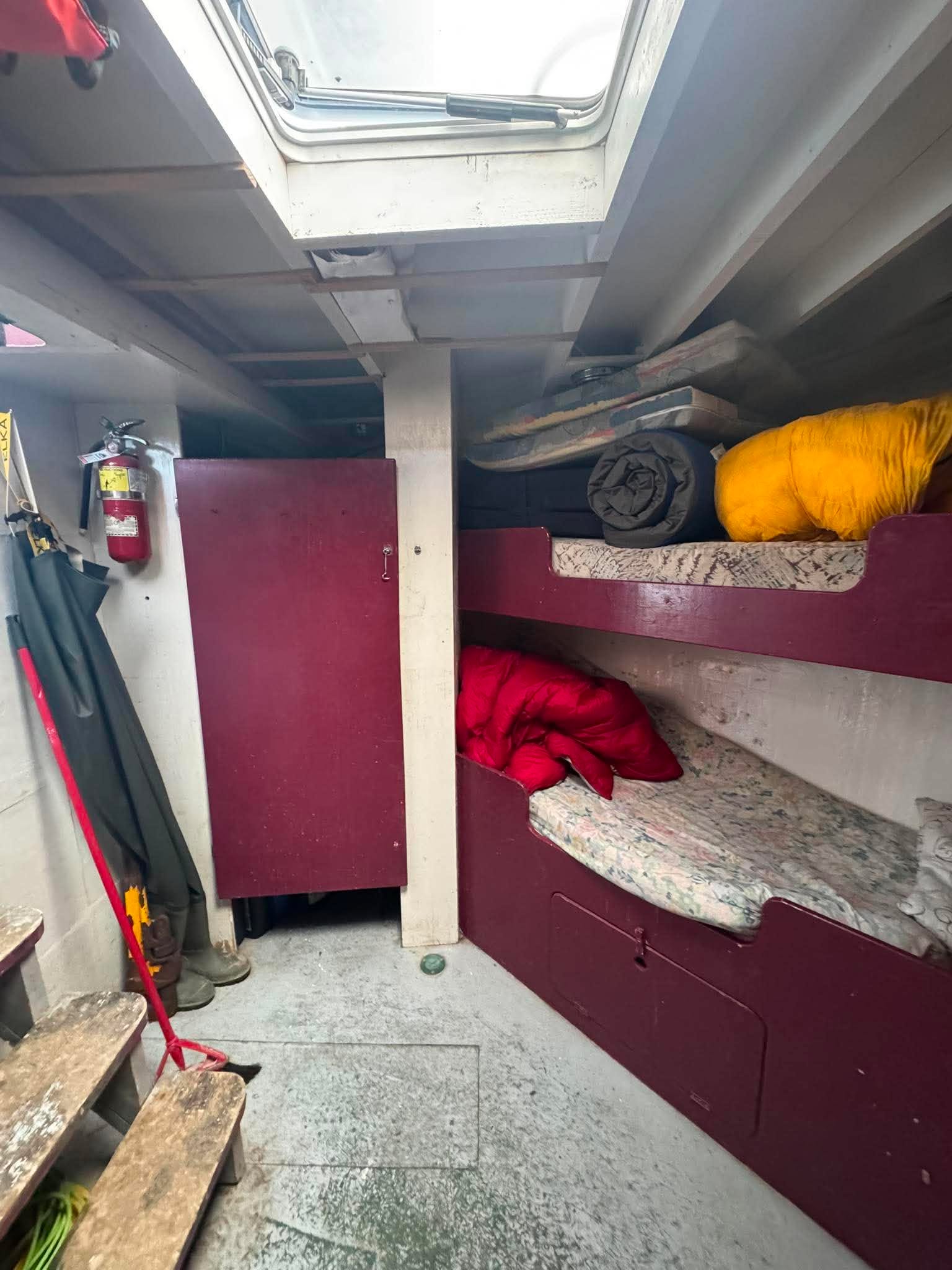 Bunk bed inside a vehicle with red blanket and yellow item on top