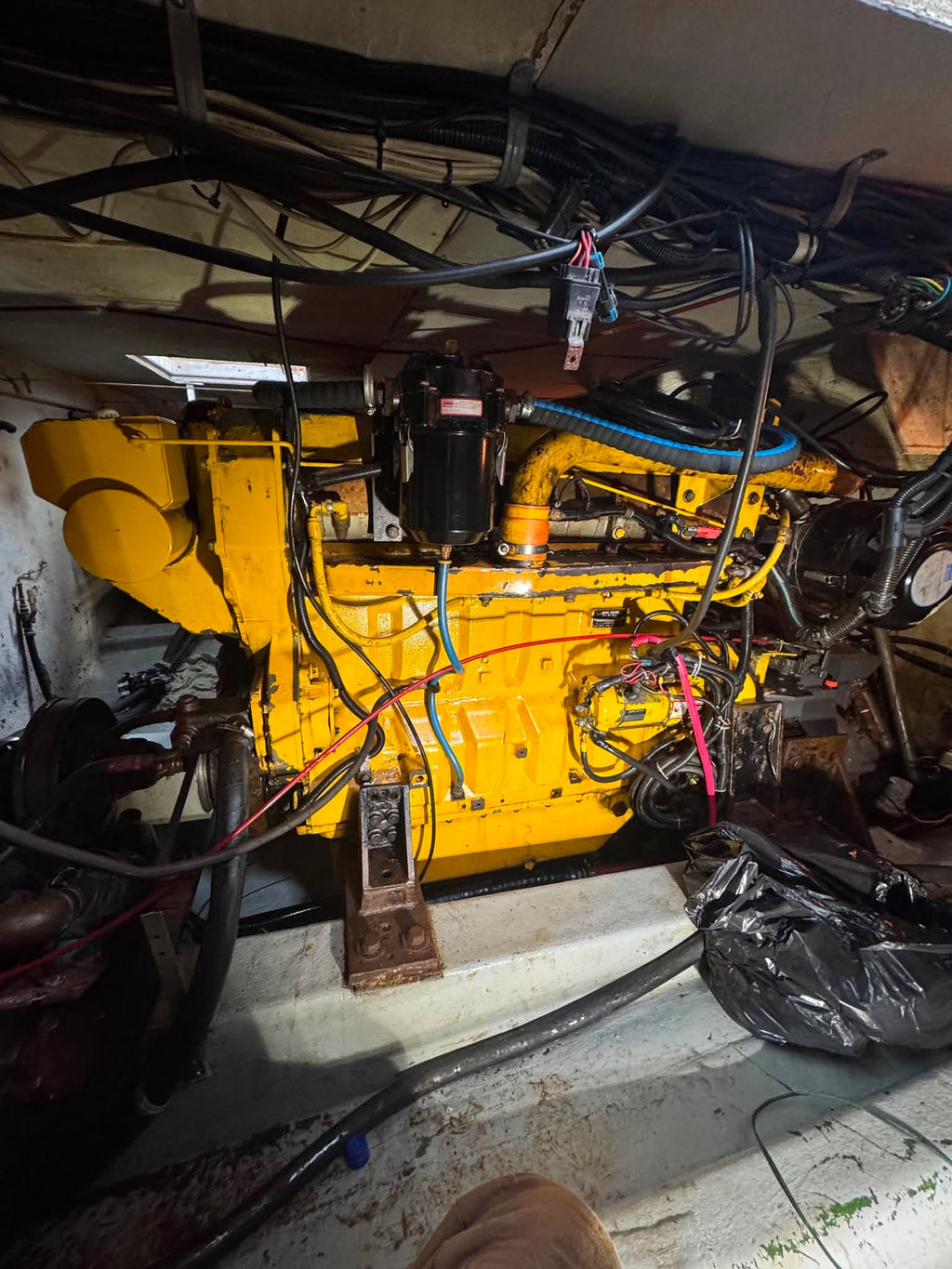 Large yellow engine in a workshop setting with various tools and equipment around.