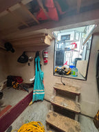 Small room with wooden steps leading to a window, various items on shelves, and a fire extinguisher on the wall.