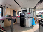 Small kitchenette inside a vehicle with a refrigerator, microwave, and table.