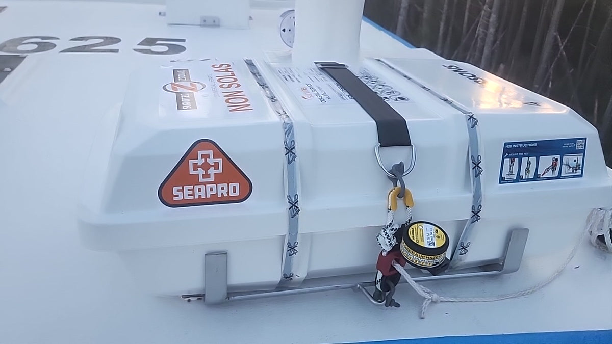 A close-up of a white SeaPro non-slip deck mat on a boat, featuring a red and orange SeaPro logo, silver straps, and a yellow-and-black hand grip.