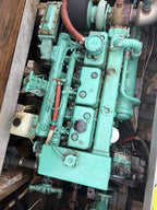 A large industrial marine engine painted in a distinctive teal green color, shown in a tight overhead view inside a boat or machinery compartment.