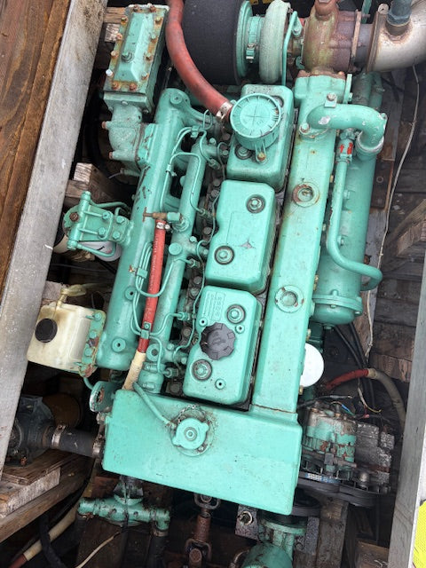 A large industrial marine engine painted in a distinctive teal green color, shown in a tight overhead view inside a boat or machinery compartment.