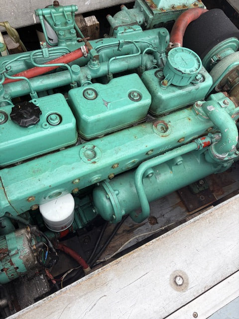 A close-up view of a large industrial engine painted in a distinctive teal-green color, showing various mechanical parts, pipes, and filters.
