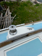Close-up of a boat's propeller and surrounding area with grass and water in the background.