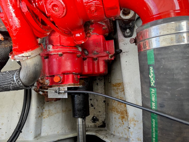 A close-up of a red engine component with a black cylindrical filter labeled 'MAXX FLOW 143' attached nearby.