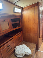 Wooden interior cabin space with storage cabinets, a slatted door panel, and a crumpled white fabric or bag on the floor.