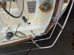 An overhead view of a boat's deck and cabin area, showing white fiberglass surfaces, dark wood trim, ropes, winches, and metal rigging over dark water.