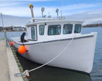 White boat tied to a dock with orange buoys on a calm water body.