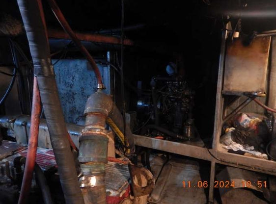 A used industrial diesel engine with attached hoses and piping, photographed in a dark, industrial setting. The image features a timestamp overlay in the bottom right corner reading '11.