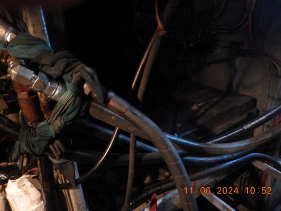 A close-up view of bundled industrial hoses and metal fittings in a dark mechanical area, with an orange timestamp in the lower right corner.