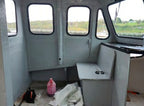Interior of a small vehicle with a bottle and tools on the floor, showing signs of repair or renovation.