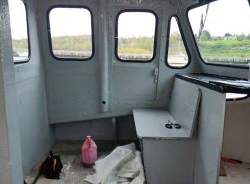 Interior of a small vehicle with a bottle and tools on the floor, showing signs of repair or renovation.