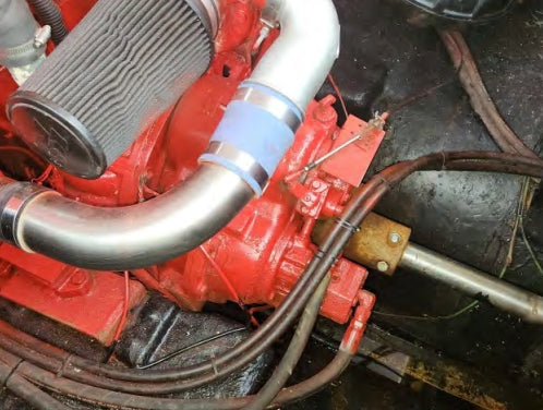 Close-up of a red engine with metal pipes and hoses.