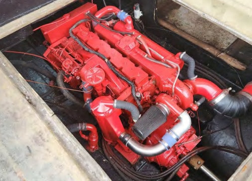 Red engine with visible components and hoses in a mechanical setting
