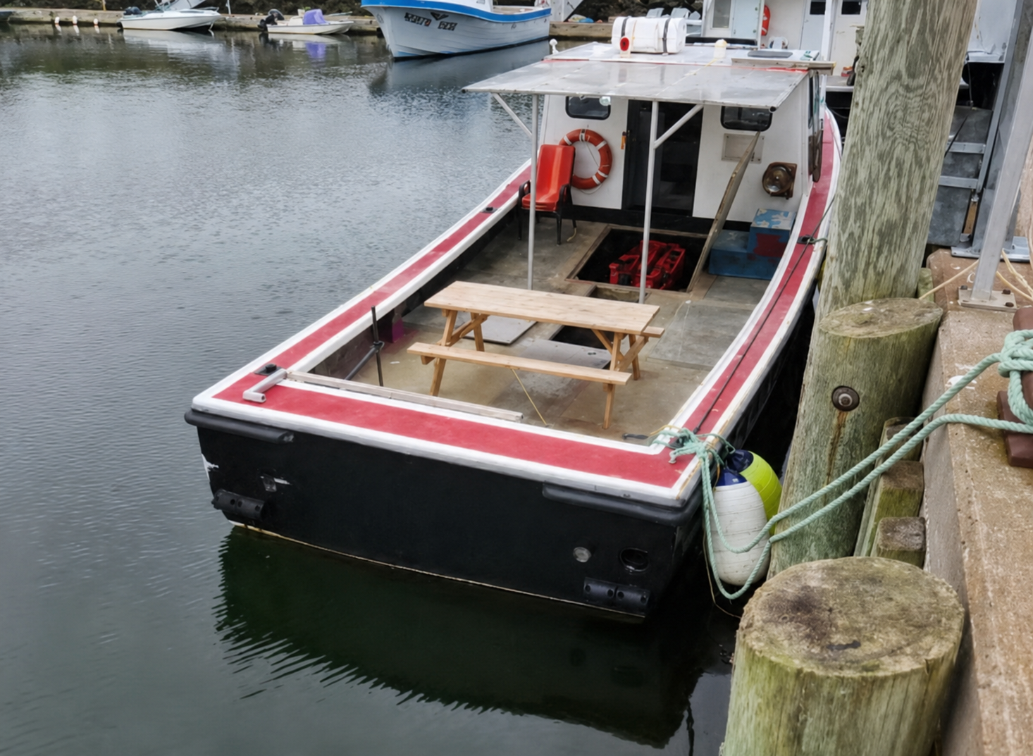 Small boat docked at a pier with a picnic table inside