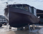 Large boat on a trailer outside a building with a snowy landscape.