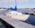 Marina scene with sailboats docked at a wooden pier on a clear day.
