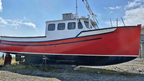 Red and white boat on a gravel surface with a blue sky background
