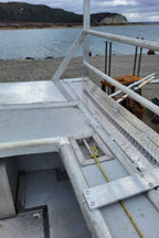 A close-up view of a white metal boat deck or railing structure near water, with a shoreline and hills in the background. The photo appears to be taken from within the boat and is shown inside a mobile app interface with an 'Edit with AI' button visible.