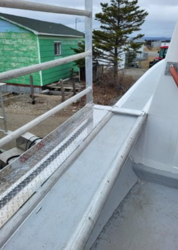 A close-up view of a white metal walkway or ramp with a diamond plate section, photographed outdoors near a green building and tree. The image appears to be a screenshot from a photo app or messaging interface, with status icons and an 'Edit with AI' button visible.