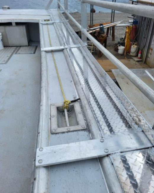 A close-up view of a metal walkway or industrial platform with diamond-plate flooring, railings, and fastened beams, shown within a phone app screenshot.