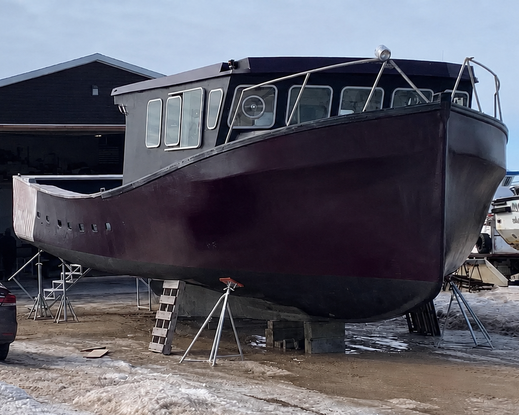 Large boat on a trailer in front of a building with snow on the ground