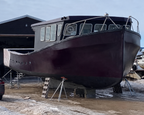 Large boat on a trailer in front of a building with snow on the ground