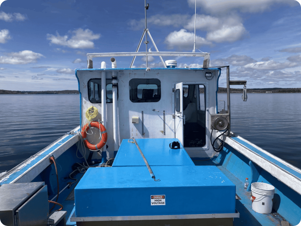 A blue and white boat cabin viewed from the deck, with an orange life preserver, blue water, and a cloudy sky in the background.