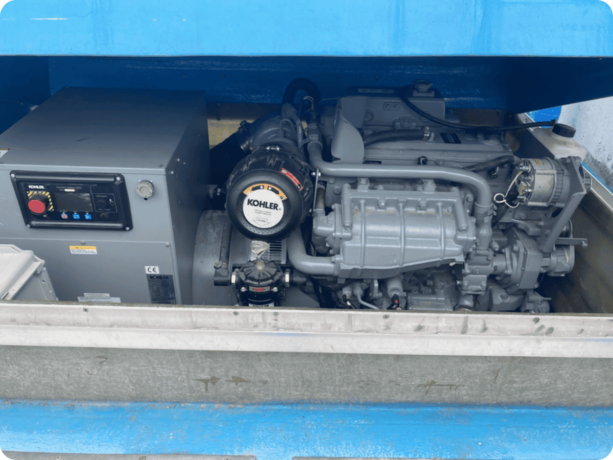A Kohles marine diesel engine and alternator unit installed inside a blue generator enclosure, with the engine bayonet visible and the alternator on the right side.